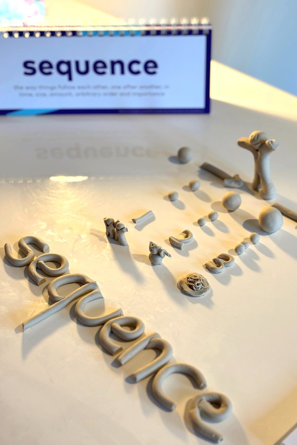 the word sequence in the background on a flipchart. With the word sequence and a sequential series of numbers modelled with clay