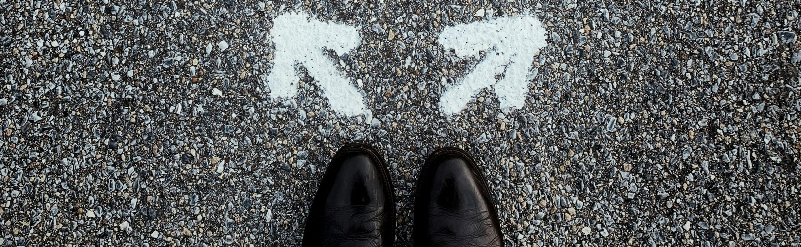 A pair of feet standing on a road with an arrow pointing left and an arrow pointing right